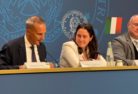 Al tavolo dei relatori durante l’evento dedicato al secondo anniversario della Carta di Solfagnano, Sergio Casagrande interviene al microfono mentre il Ministro per le Disabilità Alessandra Locatelli è seduta accanto a lui. Sul tavolo sono presenti targhette identificative, microfoni e una bottiglia d’acqua. Sullo sfondo si vedono il logo della Presidenza del Consiglio dei Ministri e la bandiera italiana.