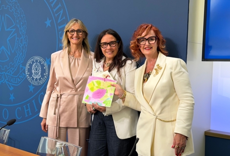 Paola e Francesca Colaiacovo posano accanto al Ministro per le Disabilità Alessandra Locatelli durante l’evento dedicato al secondo anniversario della Carta di Solfagnano. Le tre sono ritratte davanti al pannello con il logo della Presidenza del Consiglio dei Ministri e mostrano un elaborato artistico realizzato per l’occasione. La foto è scattata nella sala conferenze della Presidenza, accanto al tavolo dei relatori.