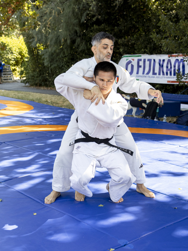 Attività di judo inclusivo durante una dimostrazione sportiva, con atleta DONG DONG CAMANNI e tecnico impegnati in un esercizio sul tatami all’aperto